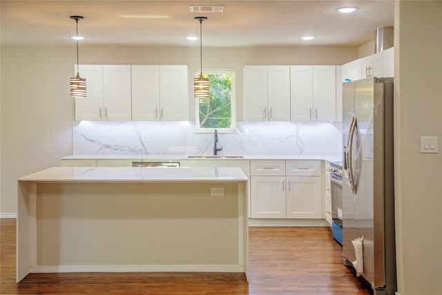 kitchen with sink, decorative light fixtures, white cabinetry, stainless steel appliances, and light stone countertops