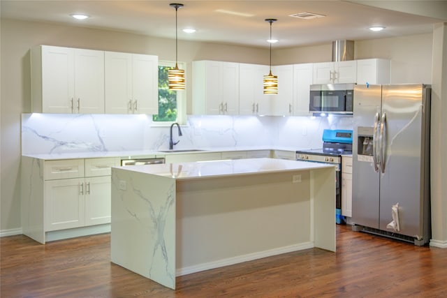 kitchen with pendant lighting, stainless steel appliances, a kitchen island, and sink