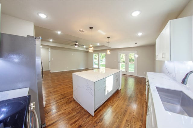 kitchen featuring ceiling fan, decorative light fixtures, dark wood-type flooring, white cabinetry, and a center island