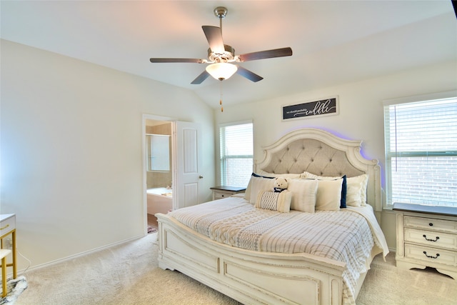 bedroom featuring vaulted ceiling, ceiling fan, light carpet, and ensuite bath