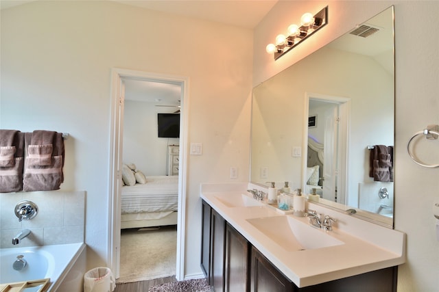 bathroom with vanity, vaulted ceiling, hardwood / wood-style floors, and a bath