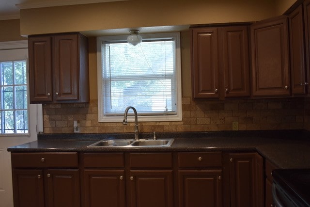 kitchen with decorative backsplash, dark brown cabinetry, and sink