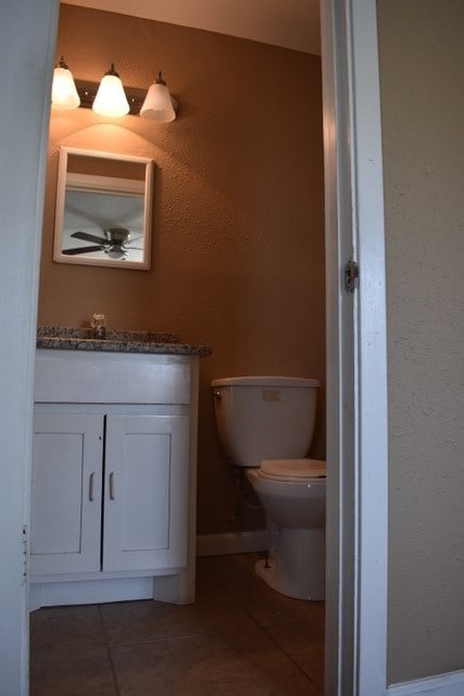 bathroom with tile patterned flooring, vanity, toilet, and ceiling fan