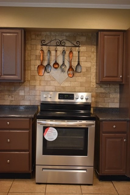 kitchen featuring backsplash, stainless steel electric range oven, dark brown cabinetry, and light tile patterned floors