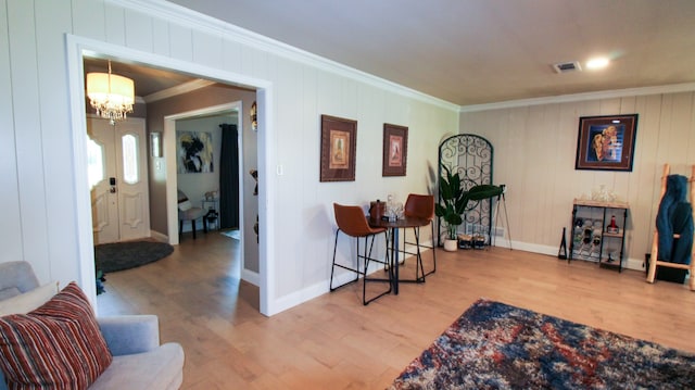 interior space with ornamental molding, a notable chandelier, and light hardwood / wood-style flooring