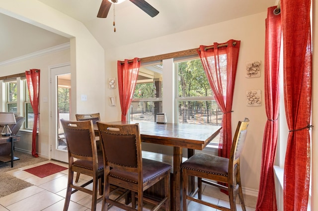 tiled dining space featuring lofted ceiling, ceiling fan, and crown molding