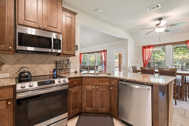 kitchen with ceiling fan, sink, kitchen peninsula, plenty of natural light, and stainless steel appliances