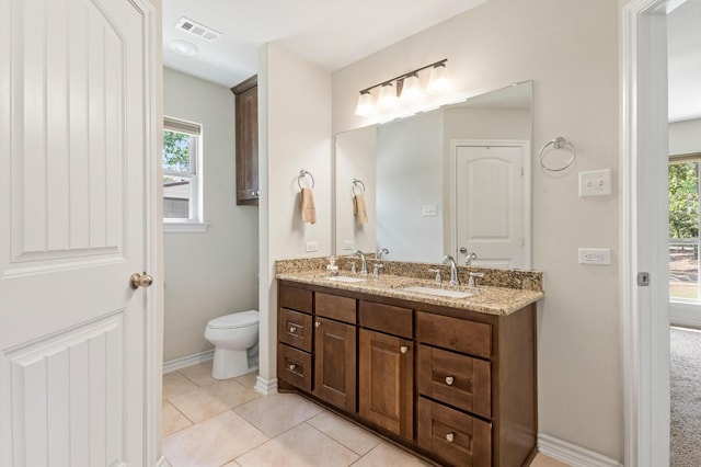 bathroom with a healthy amount of sunlight, tile patterned floors, vanity, and toilet