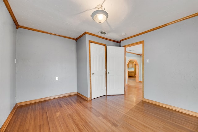 unfurnished bedroom featuring a closet, light wood-type flooring, and crown molding