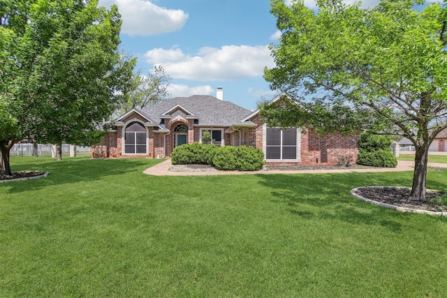 ranch-style home featuring a front lawn, brick siding, roof with shingles, and a chimney