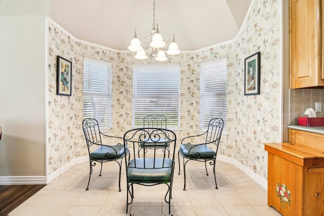 dining space with wallpapered walls, lofted ceiling, baseboards, and an inviting chandelier