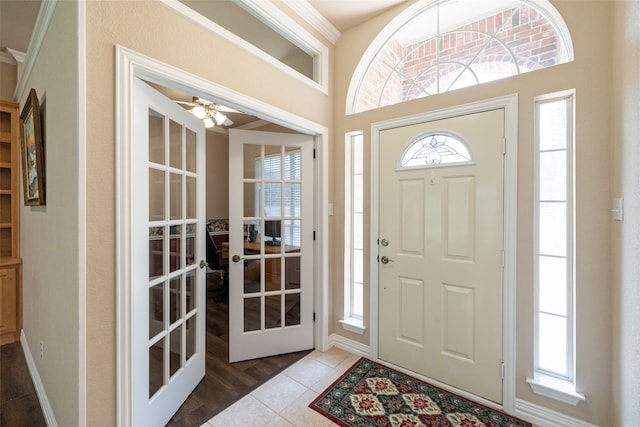 tiled foyer entrance with ceiling fan and french doors