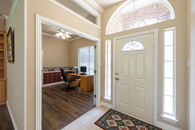 tiled entryway with ceiling fan and ornamental molding