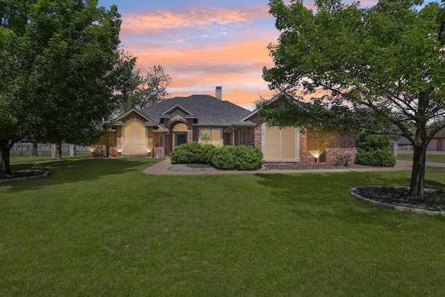 single story home featuring brick siding, a chimney, a front yard, and fence