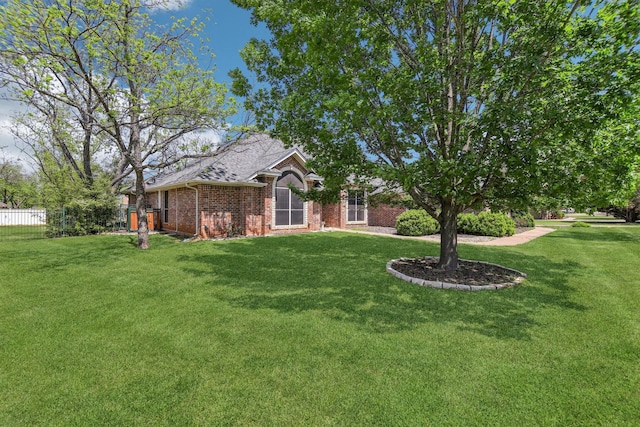 single story home with a front lawn, brick siding, fence, and roof with shingles