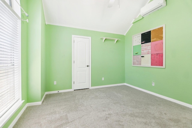spare room featuring lofted ceiling, carpet flooring, an AC wall unit, and baseboards