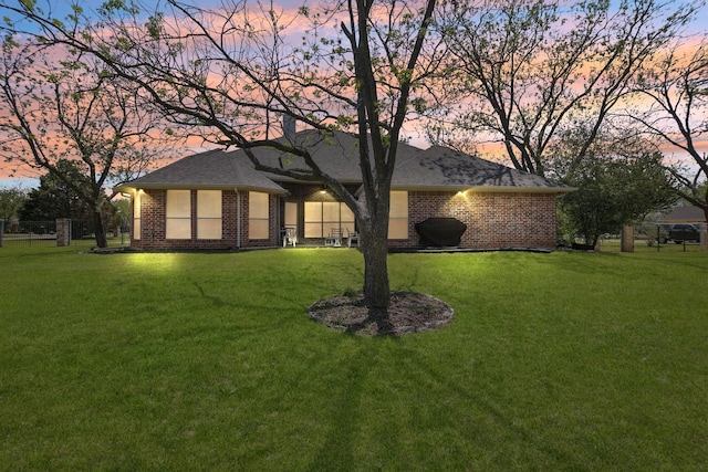 view of front facade featuring brick siding, a lawn, and roof with shingles