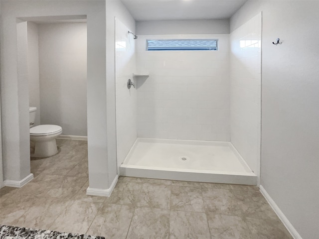 bathroom with tiled shower and toilet