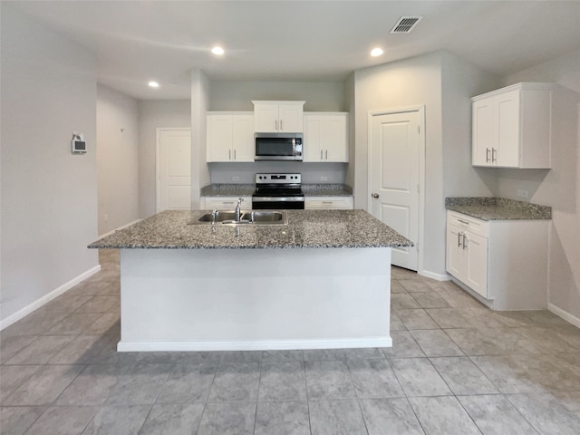 kitchen with white cabinets, appliances with stainless steel finishes, a kitchen island with sink, and sink