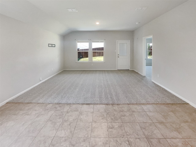 carpeted empty room featuring vaulted ceiling