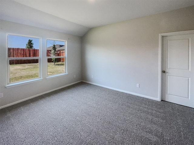 carpeted spare room featuring vaulted ceiling