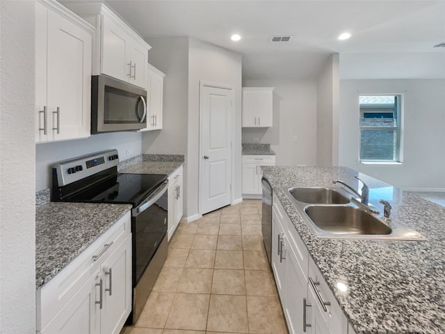 kitchen with stone countertops, stainless steel appliances, white cabinetry, and sink