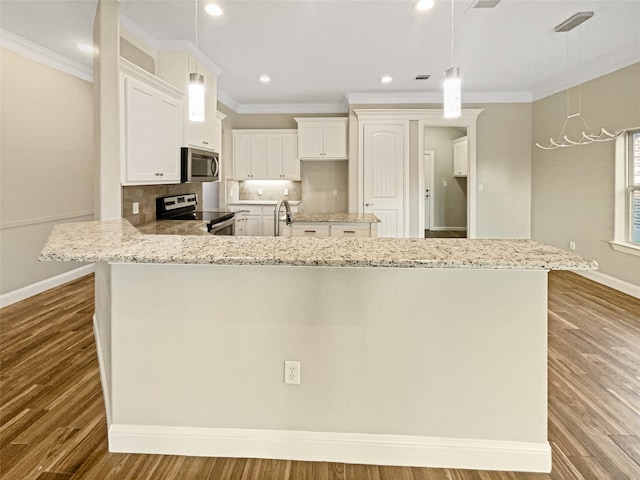 kitchen featuring pendant lighting, stainless steel appliances, ornamental molding, and hardwood / wood-style floors