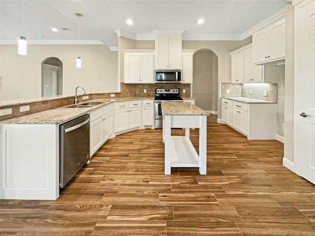 kitchen with light wood-type flooring, pendant lighting, stainless steel appliances, kitchen peninsula, and sink