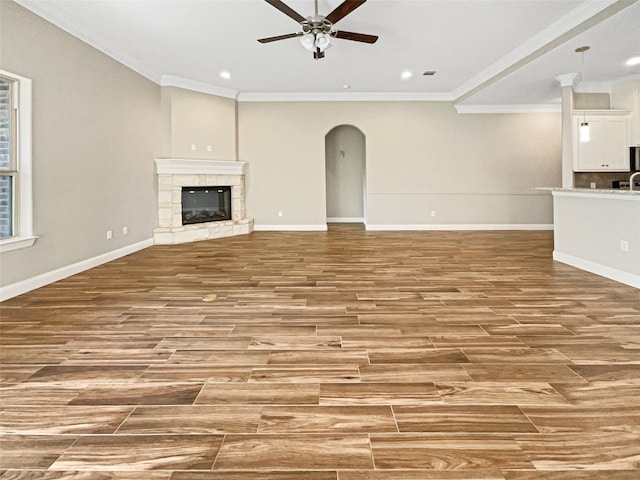 unfurnished living room with crown molding, ceiling fan, a tile fireplace, and light hardwood / wood-style floors