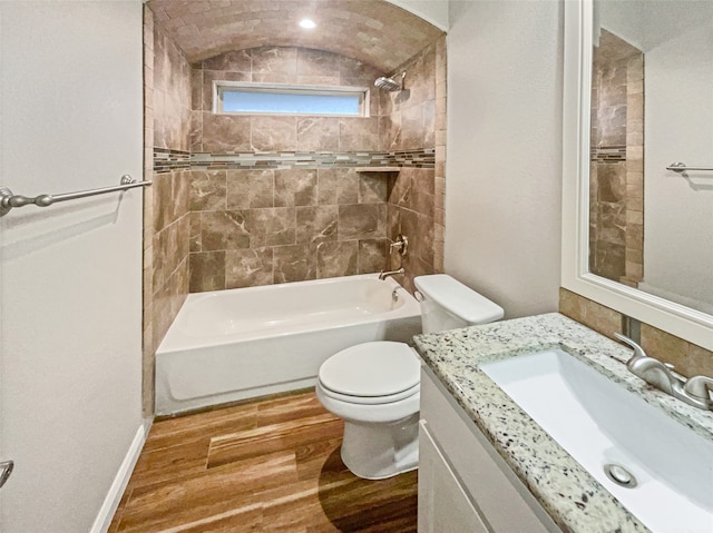 full bathroom with vanity, wood-type flooring, toilet, tiled shower / bath, and lofted ceiling