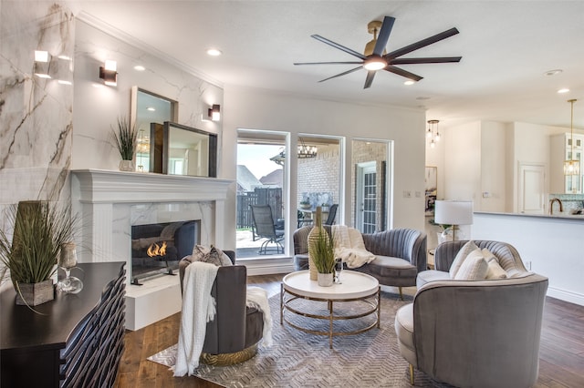 living room with ceiling fan, a high end fireplace, dark wood-type flooring, and ornamental molding