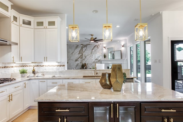 kitchen featuring white cabinets, decorative backsplash, ceiling fan, and hanging light fixtures