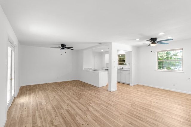 unfurnished living room featuring light hardwood / wood-style flooring, ceiling fan, and sink