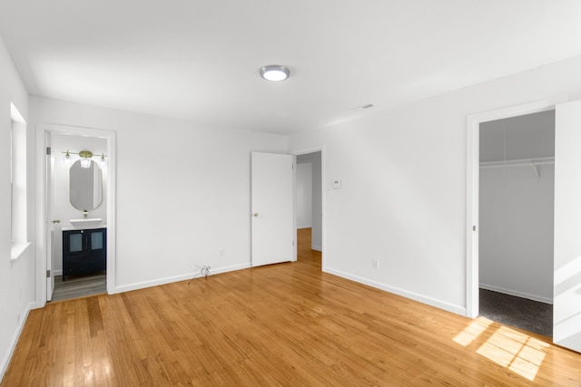 unfurnished bedroom with light hardwood / wood-style flooring, connected bathroom, sink, a closet, and a spacious closet