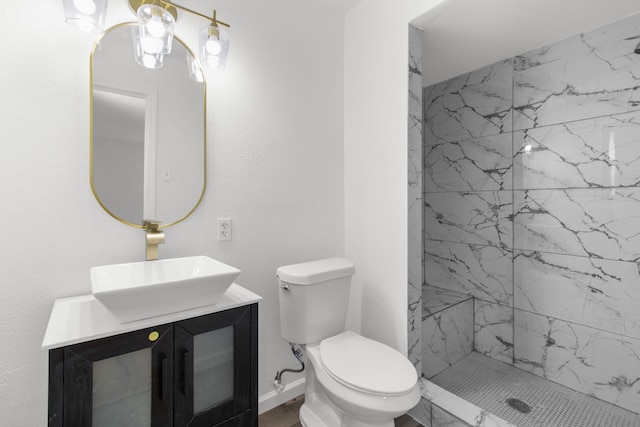 bathroom with toilet, a tile shower, and vanity