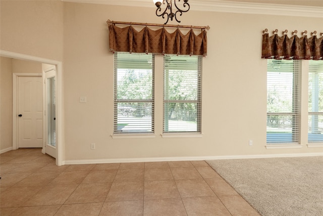 spare room featuring crown molding, a healthy amount of sunlight, light tile patterned floors, and a notable chandelier