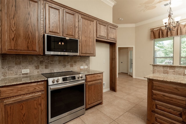 kitchen with ornamental molding, stainless steel appliances, an inviting chandelier, light stone countertops, and light tile patterned flooring