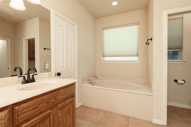 bathroom with a tub to relax in, vanity, and tile patterned floors