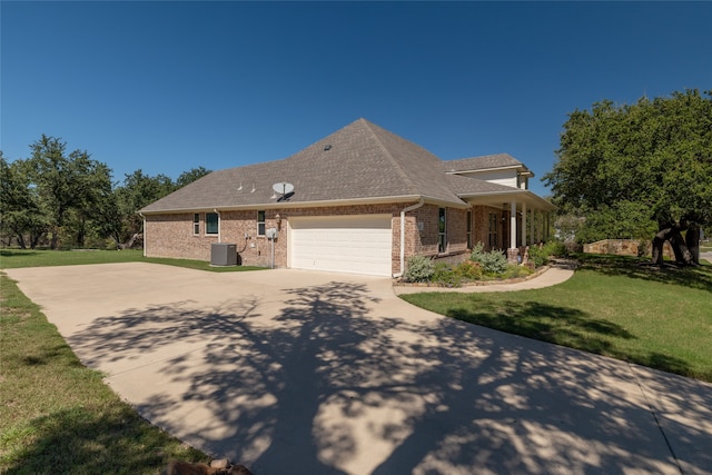 view of front of home with central AC, a front yard, and a garage