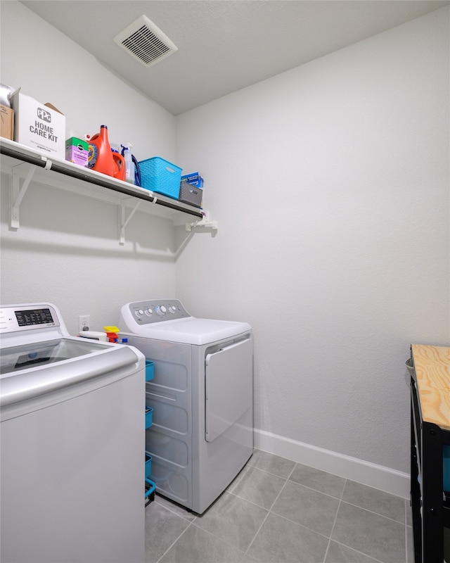 laundry room featuring washing machine and clothes dryer and light tile patterned flooring