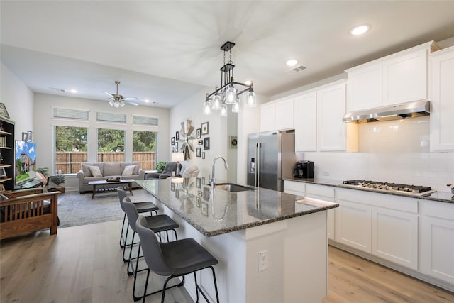 kitchen featuring a kitchen island with sink, stainless steel appliances, white cabinets, and light hardwood / wood-style floors