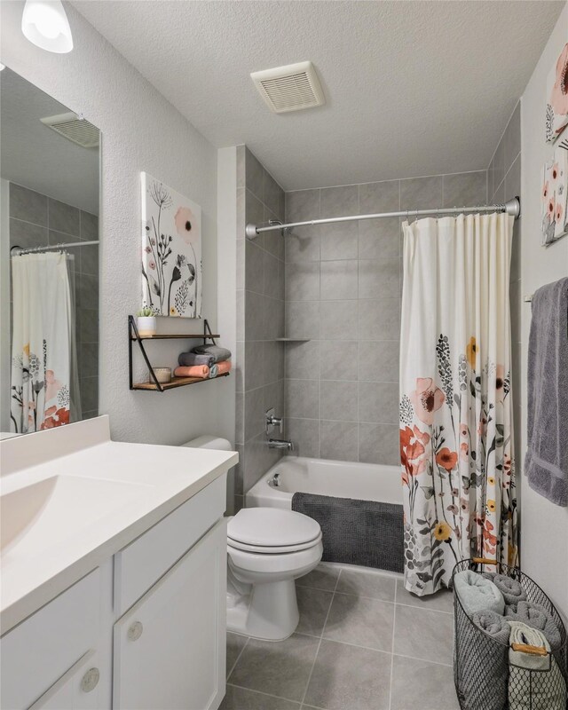 full bathroom featuring toilet, tile patterned flooring, vanity, a textured ceiling, and shower / bath combo with shower curtain