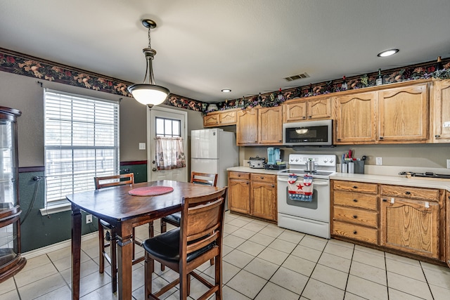 kitchen featuring white appliances, light tile patterned flooring, and decorative light fixtures