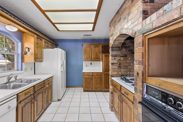 kitchen with light tile patterned floors, white appliances, sink, and a textured ceiling