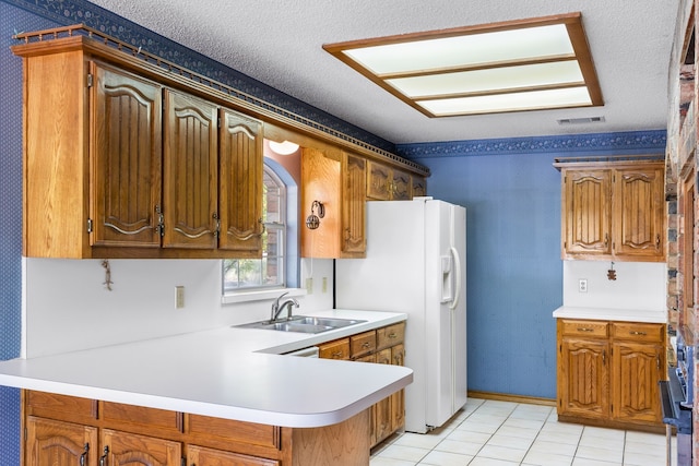 kitchen with white refrigerator with ice dispenser, a textured ceiling, light tile patterned floors, kitchen peninsula, and sink