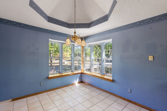 empty room featuring a tray ceiling, an inviting chandelier, a textured ceiling, and tile patterned floors