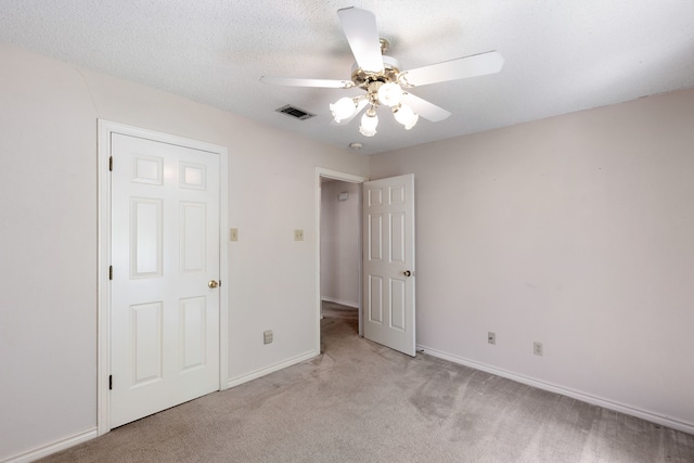 unfurnished bedroom featuring a textured ceiling, light colored carpet, and ceiling fan