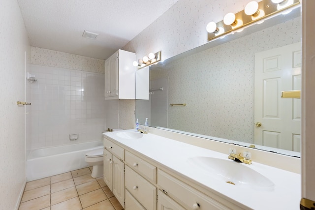 full bathroom featuring tile patterned flooring, tiled shower / bath, toilet, vanity, and a textured ceiling