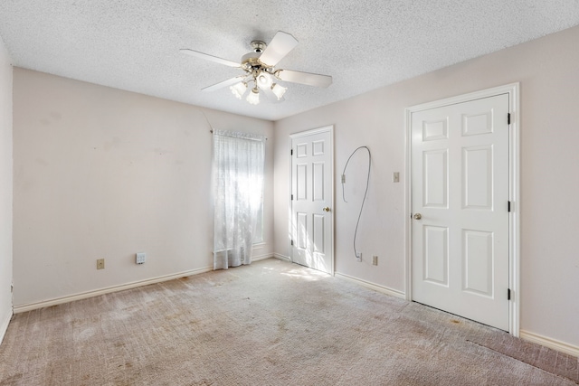 unfurnished bedroom featuring a textured ceiling, light colored carpet, and ceiling fan