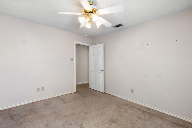 spare room featuring a textured ceiling, light colored carpet, and ceiling fan